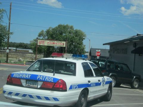 1991 Ford LTD Crown Victoria - A police car with "Highway Patrol" and "DPS Arizona" markings is parked in front of a steak house.