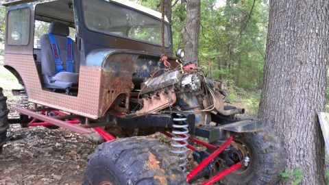 1978 Ford Bronco - This heavily modified off-road vehicle is suspended by a chain, showing its exposed engine and large tires.