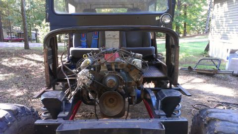 1978 Ford Bronco - The engine bay and interior of a vehicle are visible from the rear, showing exposed mechanical components and racing seats.