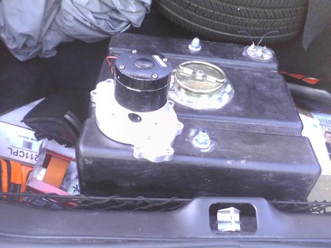 2003 Ford Crown Victoria - A fuel tank and pump assembly are stored in the trunk of a vehicle, alongside other items.