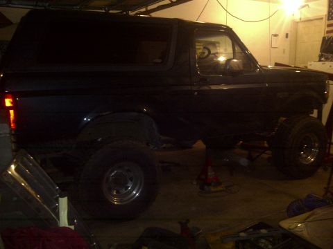 1995 Ford Bronco - This dark SUV, likely a 1992 model, is elevated on jacks for maintenance or modification.