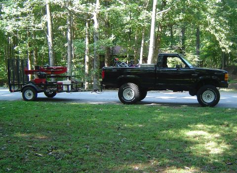 1989 Ford Ranger - A black 1989 Ford Ranger is seen from the side, towing a trailer equipped with a log splitter and other equipment.