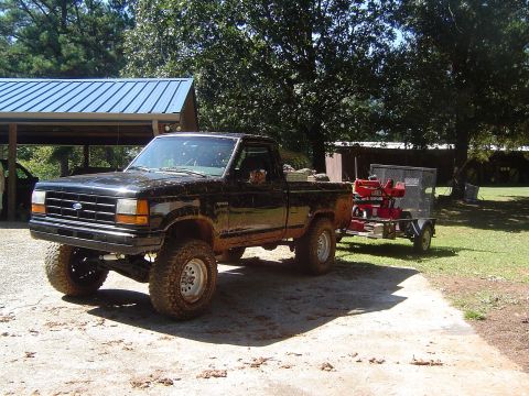 1989 Ford Ranger - A lifted black 1989 Ford Ranger is shown towing a log splitter on a trailer in a rural setting.