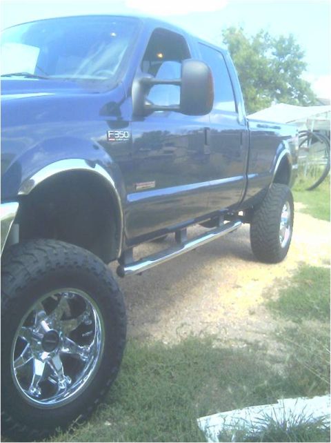 2004 Ford F-350 - Side view of a blue 2004 Ford F-350 pickup truck with custom wheels and side steps.
