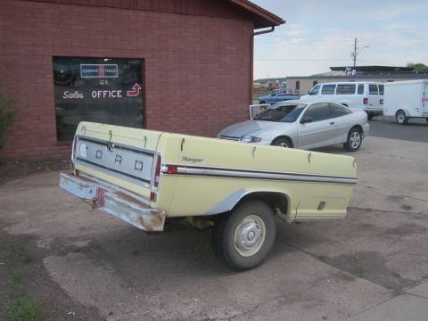 1991 Ford LTD Crown Victoria - This 1970s Ford pickup truck is parked in front of a building with "Cooper Tires" signage.