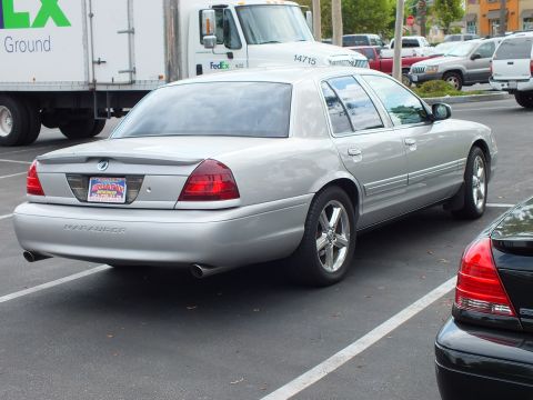2003 Ford Crown Victoria - Silver Marauder sedan on chrome five-spoke wheels parked near FedEx trucks, rear quarter view