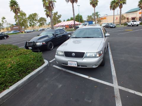 2003 Ford Crown Victoria - Silver sedan with Mercury grille badge and plate 5UGF178; a black sedan with push bar sits to the left.