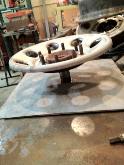 1989 Ford Bronco - A wheel hub assembly with lug nuts is shown on a workbench.