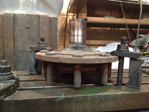 1989 Ford Bronco - A rusty wheel hub assembly is secured with clamps on a machine table, indicating mechanical work.