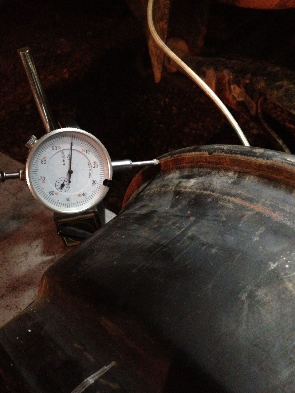 Dial indicator measuring a black rim with rust detail