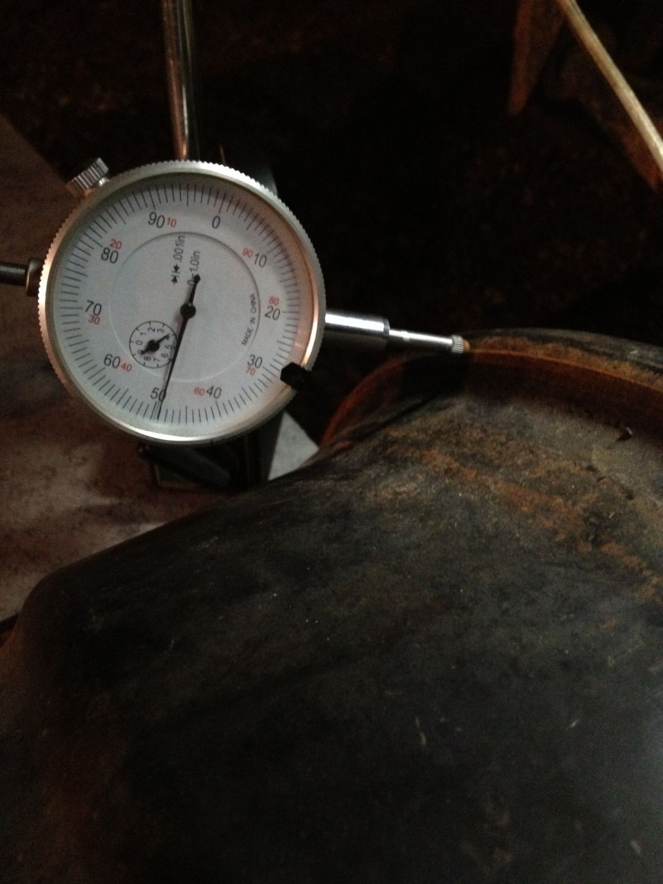Dial indicator measuring a dark, possibly metal, curved surface. Text on dial reads '0.001in'