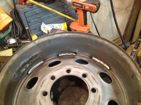 1989 Ford Bronco - A steel wheel shows signs of repair with multiple welds along its inner edge.