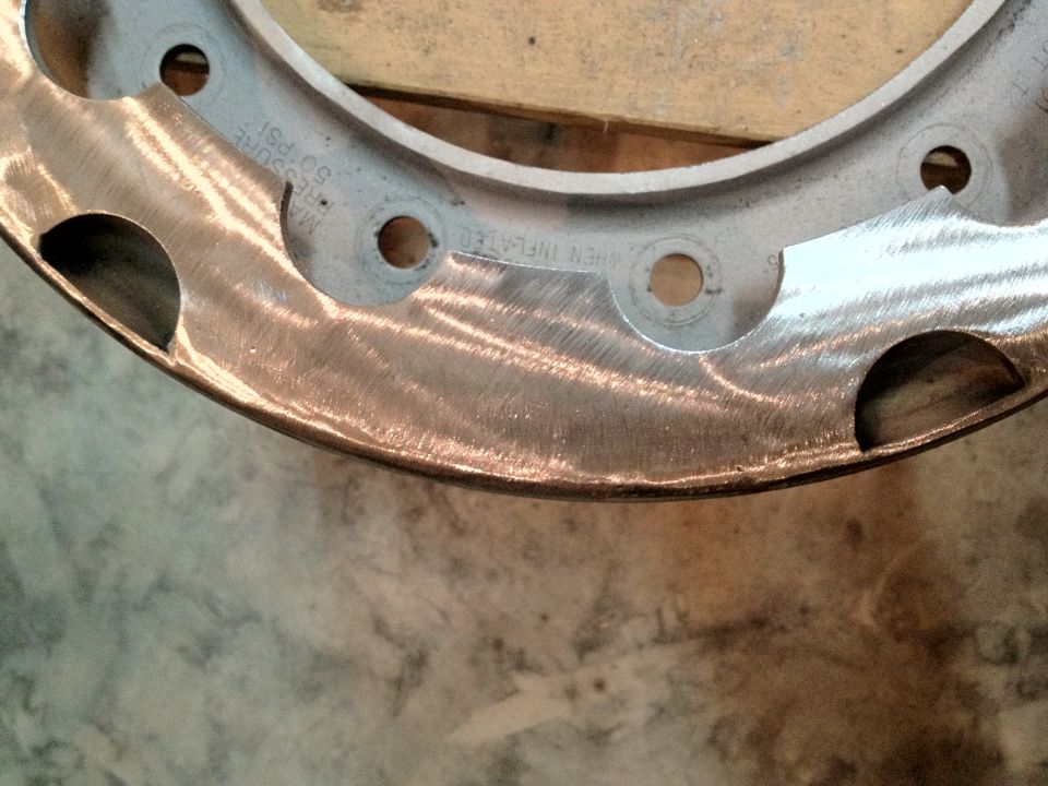 Close-up of a metal wheel rim with some scuff marks and text stamped on it
