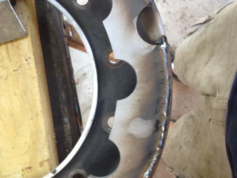 1989 Ford Bronco - Metal wheel rim with circular cutouts and weld marks, likely a custom modification.