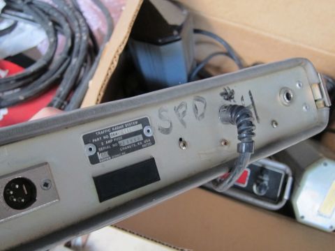 1991 Ford LTD Crown Victoria - Close-up of a Kustom Signals traffic radar system unit, showing its rear panel with identification labels and handwritten markings.