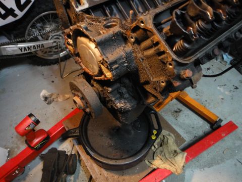 1994 Ford Bronco - Engine block assembly is shown on a stand, with a drain pan underneath and a motorcycle in the background.