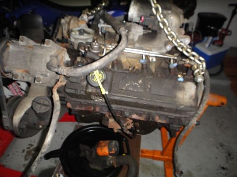 1994 Ford Bronco - Engine assembly with various hoses and a chain hoist attachment.