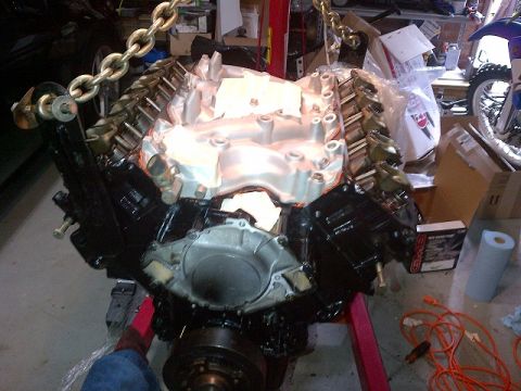 1994 Ford Bronco - Engine assembly being worked on, suspended by chains on an engine stand.