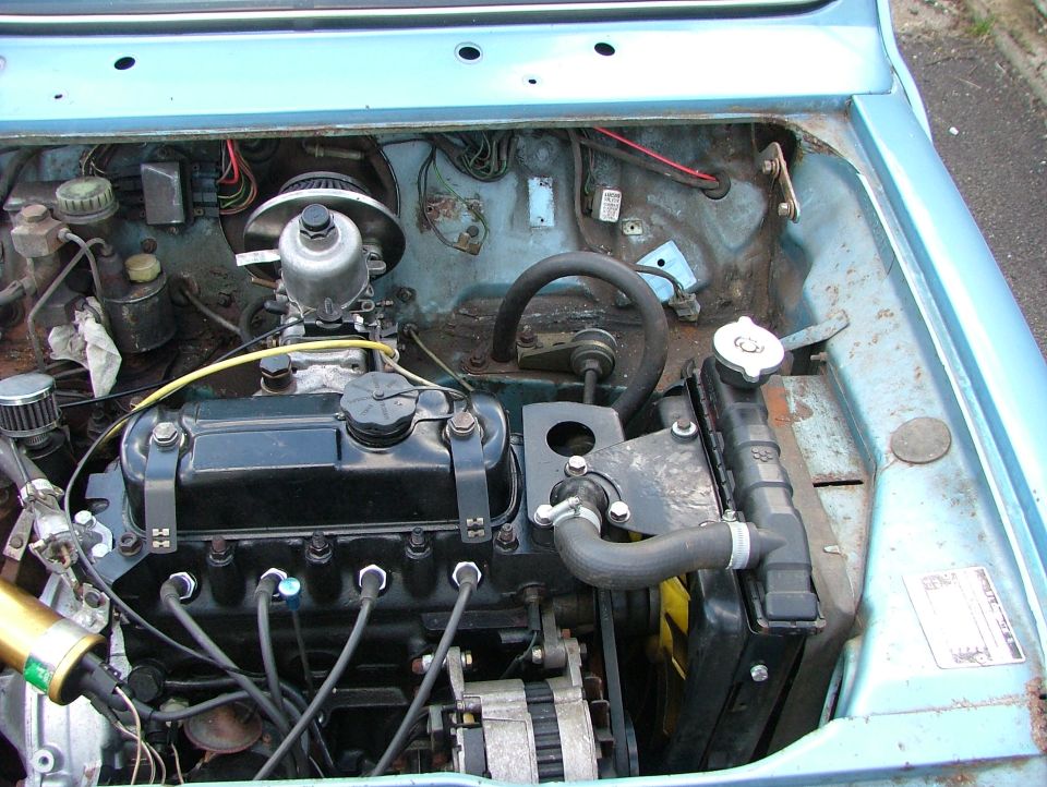 Classic Mini engine bay with transverse A-series engine and light blue rusty bodywork