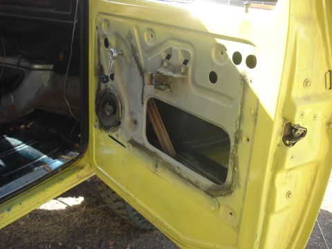1978 Ford Bronco - The interior of a yellow vehicle's door is exposed, revealing the inner workings and a speaker.