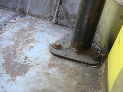 1978 Ford Bronco - Close-up view of a rusty metal plate bolted to the interior floor, likely a mounting point for a roll bar.