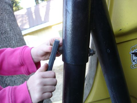 1978 Ford Bronco - A child works on a black metal bar with a wrench, with a yellow vehicle visible in the background.