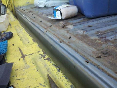 1978 Ford Bronco - Close-up of a truck bed's interior, showing yellow paint and a metal trim piece.