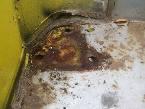 1978 Ford Bronco - Close-up view of a heavily rusted metal floor pan, showing signs of wear and tear.