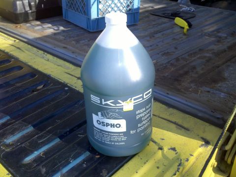 1978 Ford Bronco - A bottle of Skyco Ospho rust treatment is placed in the bed of a pickup truck, alongside other items.