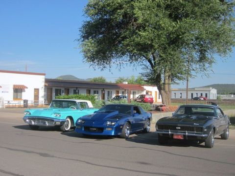 1991 Ford LTD Crown Victoria - Three classic American cars, including a black 1967 Camaro SS, a blue Camaro, and a turquoise convertible, are parked outside a motel on a…