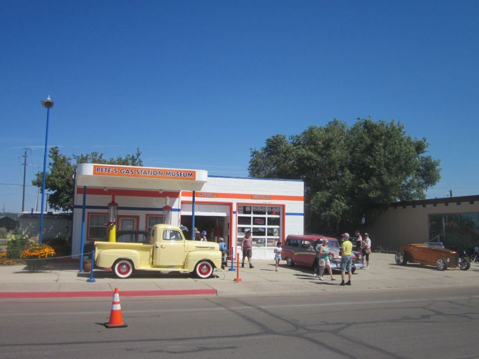 Pete's Gas Station Museum with a yellow pickup, red van, and orange hot rod parked outside