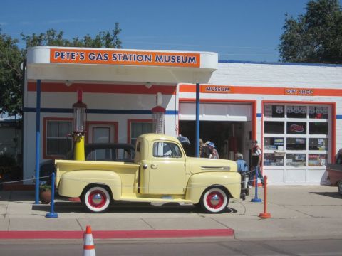 1991 Ford LTD Crown Victoria - A vintage yellow pickup truck is parked outside a classic gas station museum.