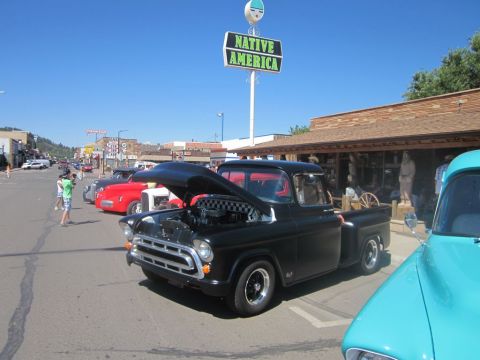 1991 Ford LTD Crown Victoria - Classic car show features a black 1955 Chevrolet pickup truck with its hood open.
