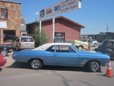 1991 Ford LTD Crown Victoria - A light blue coupe with a white vinyl roof is parked in front of a business with a large sign.