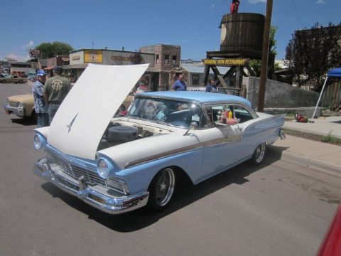1991 Ford LTD Crown Victoria - A classic two-tone blue and white Ford Fairlane coupe is displayed with its hood open at an outdoor car show.