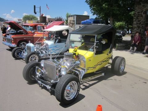 1991 Ford LTD Crown Victoria - Multiple custom hot rod vehicles displayed at an outdoor car show on a sunny day.
