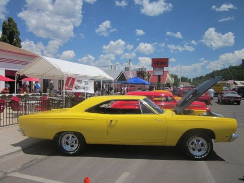 1991 Ford LTD Crown Victoria - A yellow muscle car is parked at an outdoor event with a diner in the background.