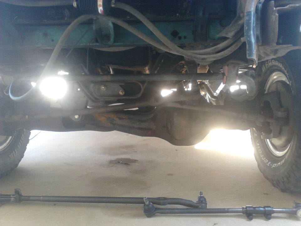 Stock steering after 6" lift. the long passenger side inner tie rod was slightly bent but not easily seen in the picture. I wanted to do a Tie Rod End flip to help straighten my steering out after the lift. Tie Rods were also worn out. Figuered it was a perfect time to upgrade the steering.

On the floor is the new bigger tie rods. they definatly are quite ticker than stock so they shouldnt bend nearly as easy.

I wont cover how to remove the tie rods. its pretty easy jsut to bang them out with a hammer once the nut is removed. the stud going into the pitman arm can be very difficult and best bet is a pickel fork. i didnt have a one with me so i used a bit adjsutable wrench as one.