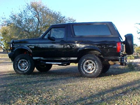 1995 Ford Bronco - Side profile of a black 1995 Ford Bronco, a spare tire mounted on the tailgate.