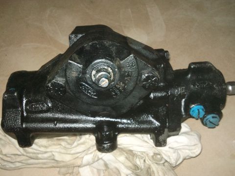 1998 Ford Crown Victoria - Close-up of a black steering gear assembly, likely for a Ford vehicle, showing cast-in logos and part numbers.