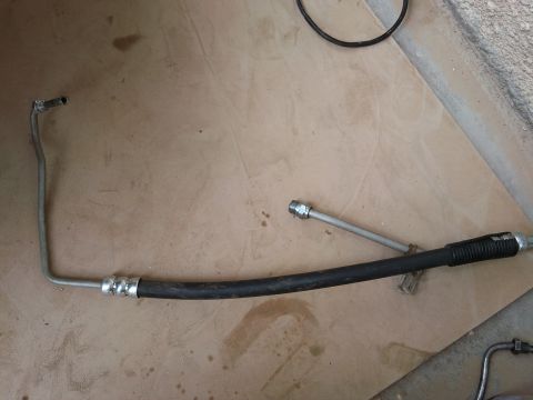 1998 Ford Crown Victoria - A power steering hose assembly is laid out on a brown surface.