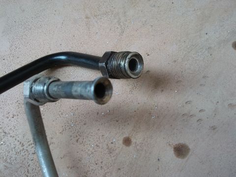 1998 Ford Crown Victoria - Close-up view of two metal hoses, likely for a vehicle's fluid system, with threaded connectors.