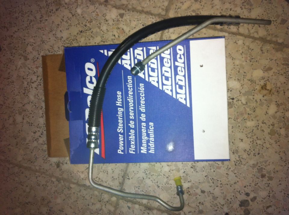 Power steering hose with ACDelco box. Black ribbed hose connects to metal tubing with a yellow cap