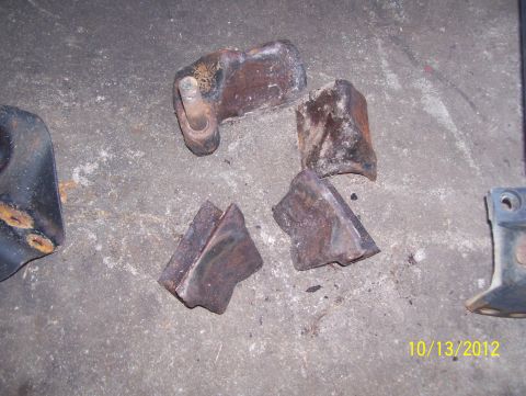 1990 Ford Bronco - Rusted metal parts are scattered on a concrete surface, possibly from a vehicle.