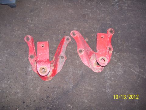 1990 Ford Bronco - Pair of red metal suspension brackets shown on a concrete floor.