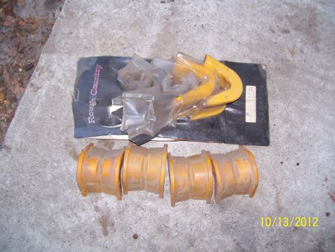 1990 Ford Bronco - Worn yellow poly suspension bushings laid out next to a Rough Country bushing kit on concrete.