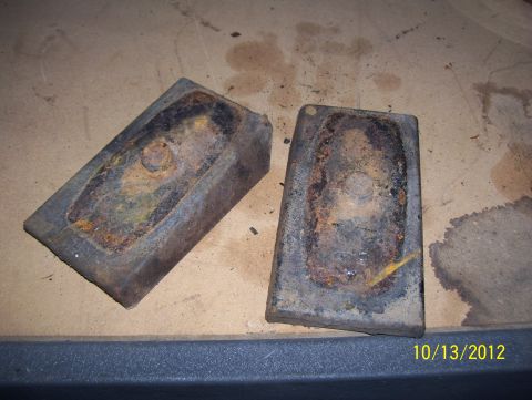 1990 Ford Bronco - These two rusty metal parts are shown on a flat surface with some stains.