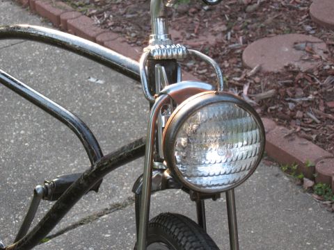 1994 Ford Bronco - A custom bicycle with a large, round headlight is parked outdoors on a paved surface.
