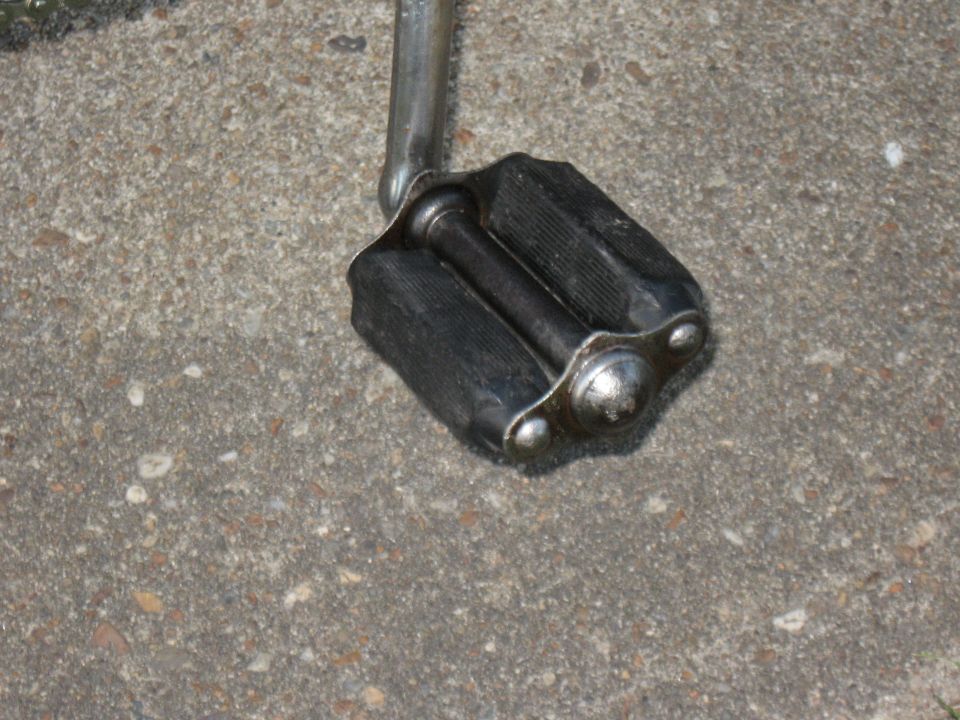 Bicycle pedal with black rubber grips and chrome accents on concrete