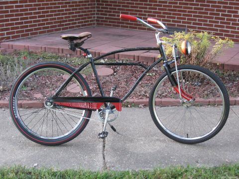 1994 Ford Bronco - A black bicycle with red handlebars and accents, a vintage headlight and Bontrager tires, is parked on a sidewalk.